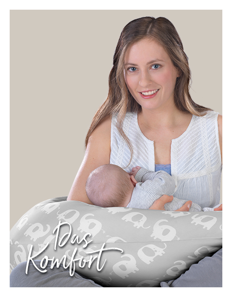 Eine Frau hält ein Baby, das auf einem Theraline Stillkissen mit Elefantenmuster liegt. Der Hintergrund ist einfarbig beige. Text: \